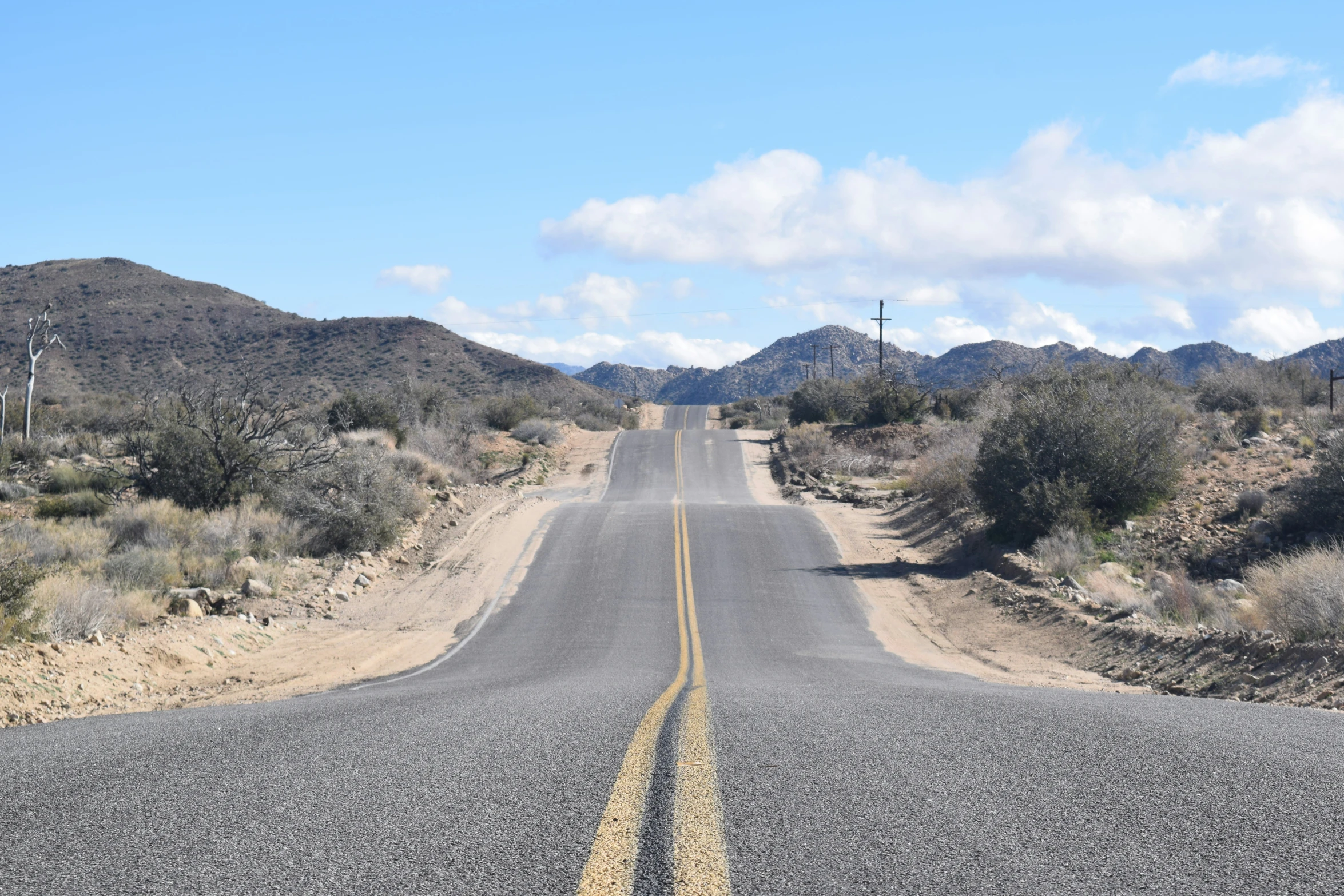 an empty road that is next to some mountains