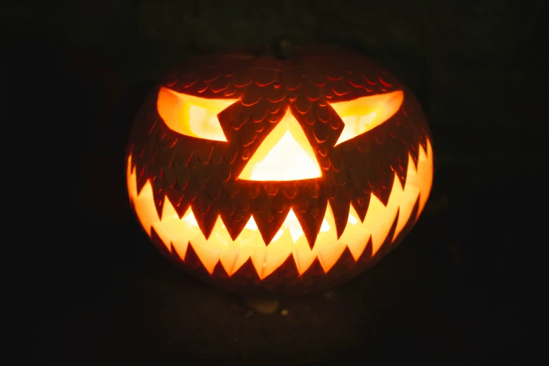 a carved pumpkin with a devil's head lit