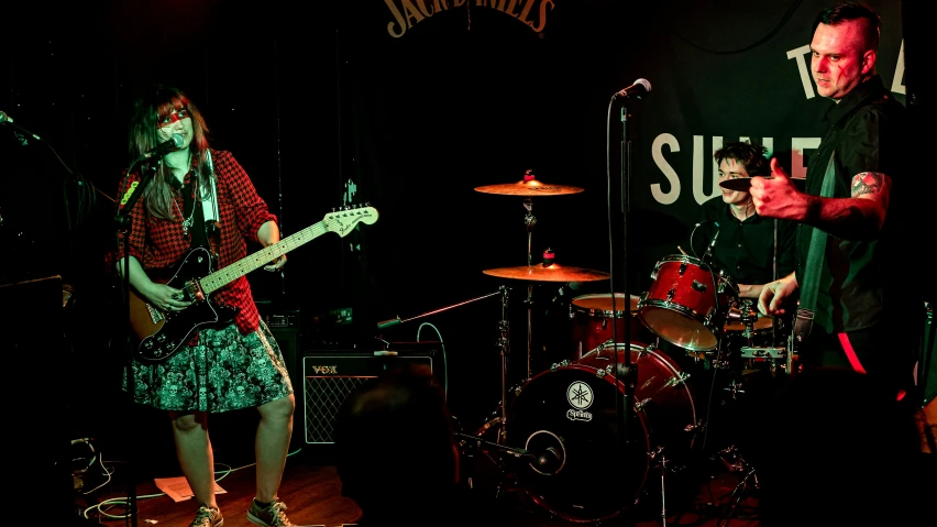 three people on stage playing instruments and singing