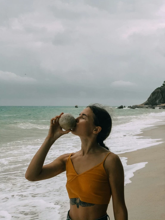 a woman drinking a cup on the beach