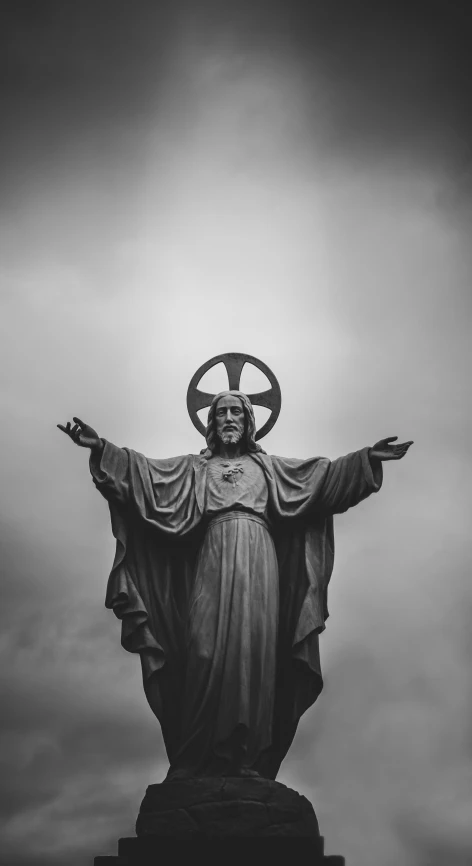 a statue with the words'jesus is standing up against a gray sky '