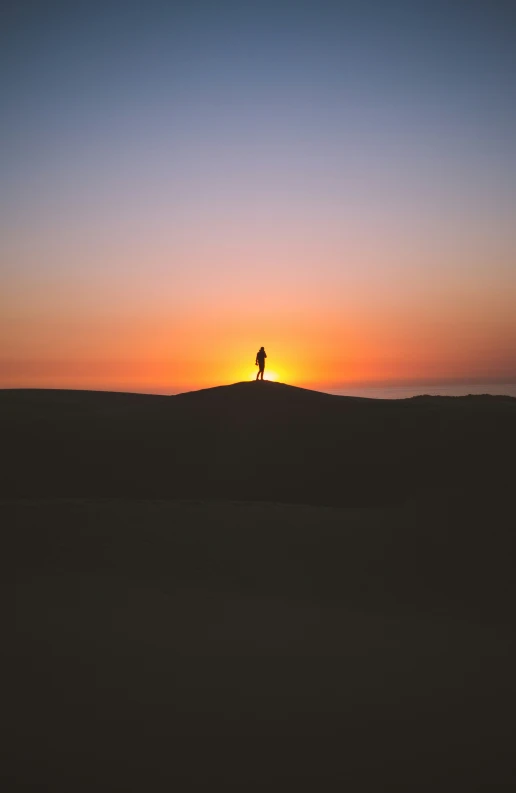 a person on top of a sand dune watching the sun rise