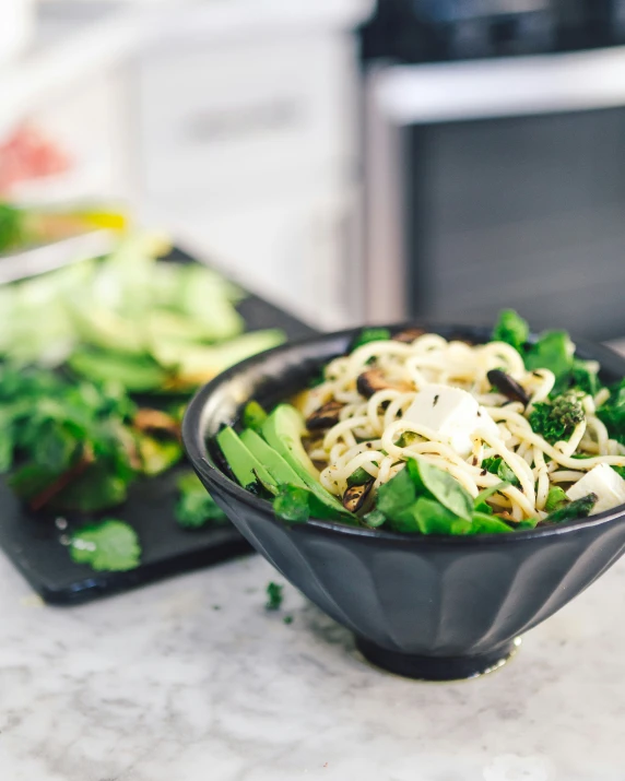 a bowl of salad sitting next to a black plate