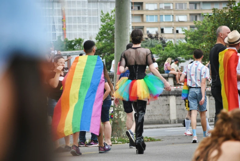 the person in the black tank top is carrying a rainbow flag