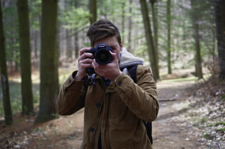 a man in the woods taking a po with his camera