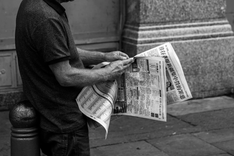 man looking down at the newspapers he is holding