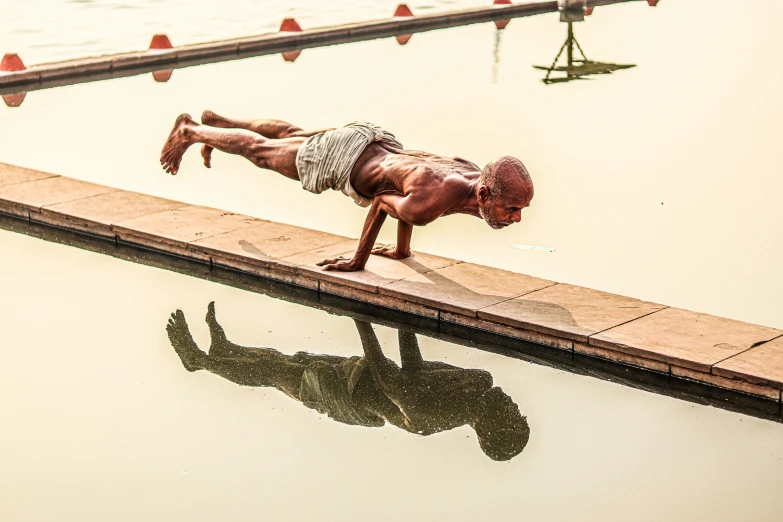 a man doing a handstand while on the side of a swimming pool