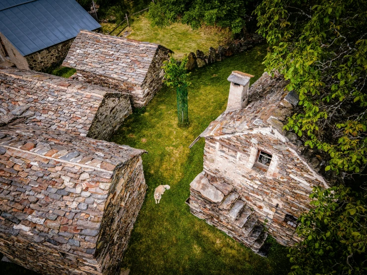 an aerial view of a grassy field, with abandoned buildings