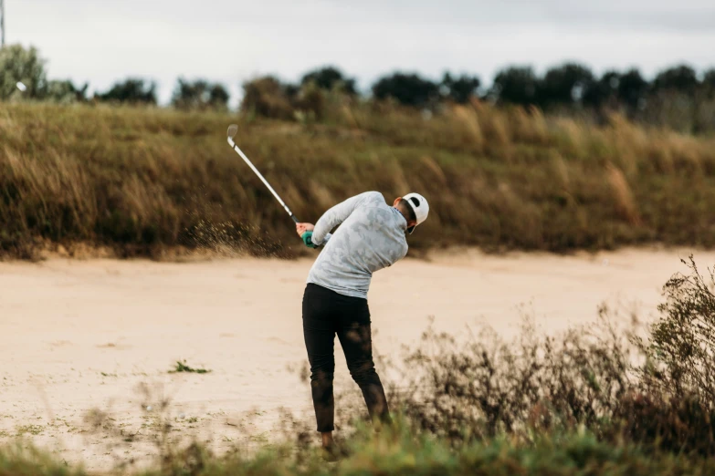 a man playing golf in the sand