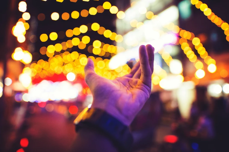 a hand is shown with many different colored lights in the background