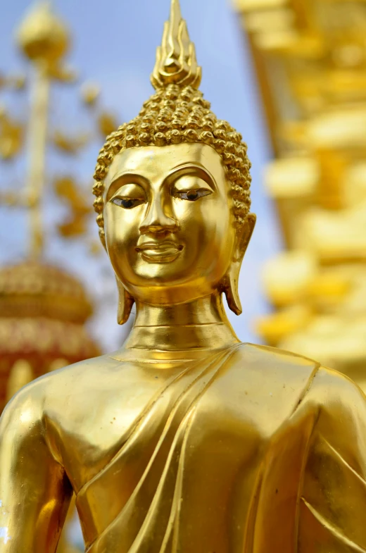 golden buddha statue in front of gold columns and crosses