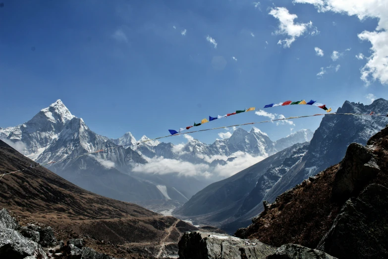 there is a long stream of colorful flags by the mountains