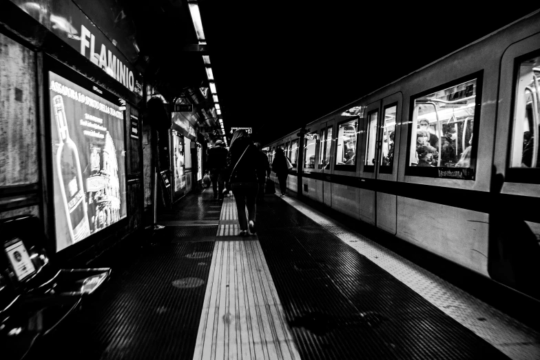 some people are walking next to the trains