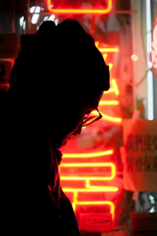 a person standing next to a sign with neon signs in the background