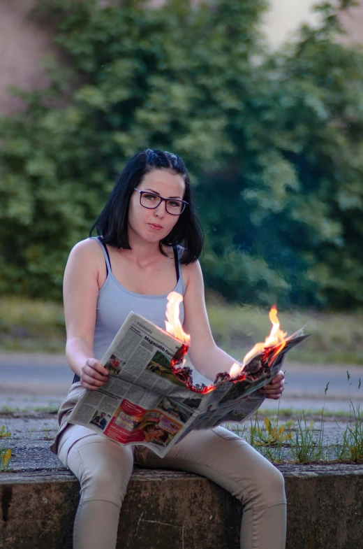 a woman with glasses is sitting down reading the newspaper