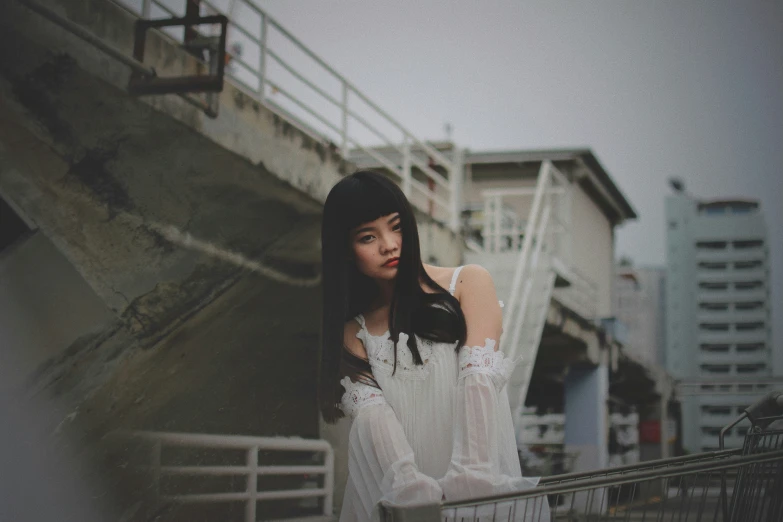 a woman standing on the side of a road next to a wall