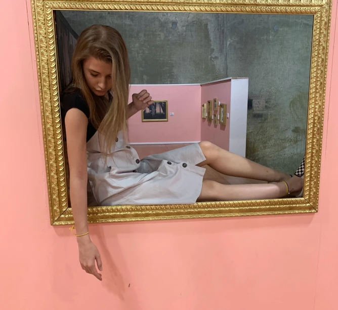 a woman with blond hair holding a pink box in a mirror
