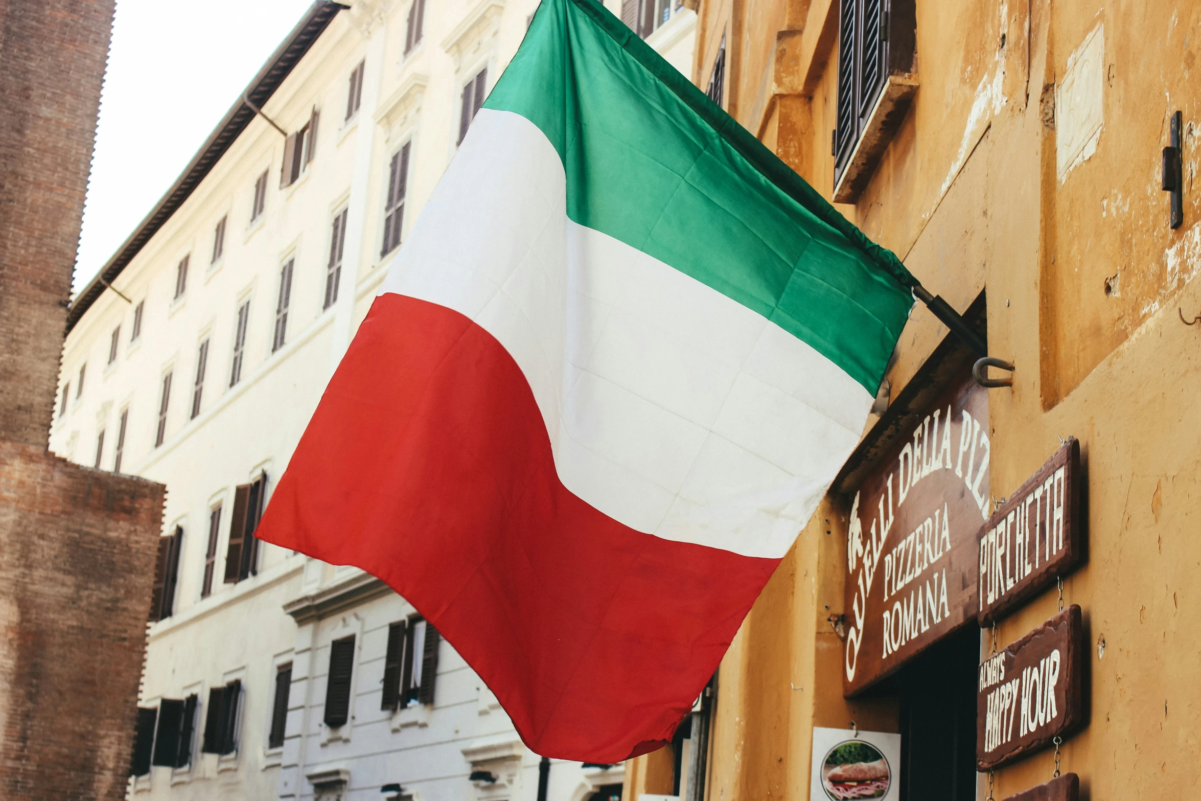 a flag hangs outside of an italian restaurant