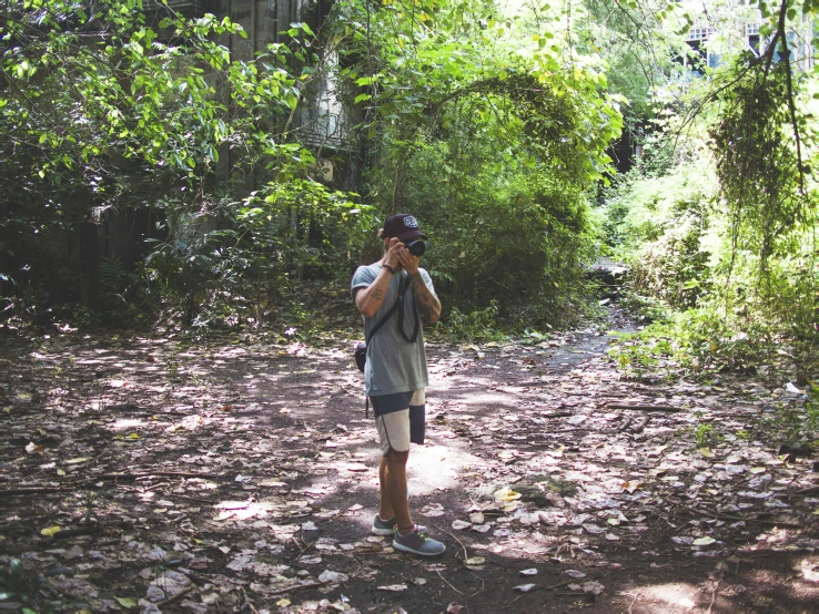 a person with a camera on his shoulder standing in the middle of the woods