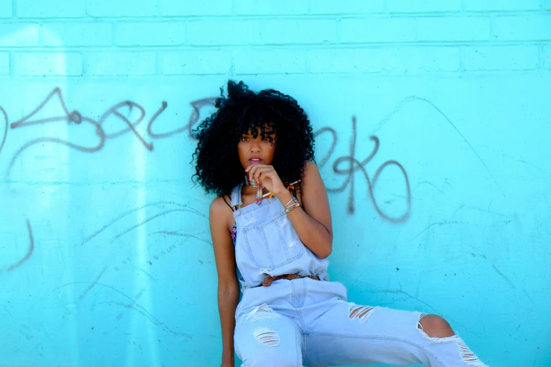 a young woman leaning against a wall with her hand on the ground