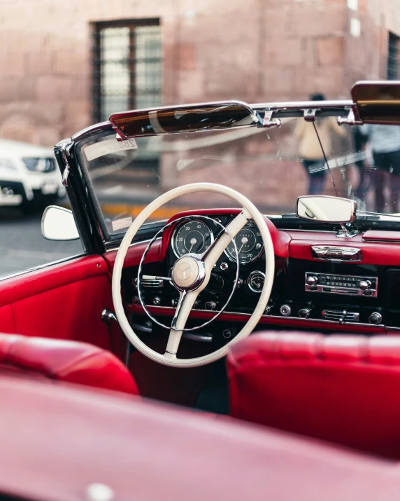 a red convertible car with leather seats, steering wheel and dashboard