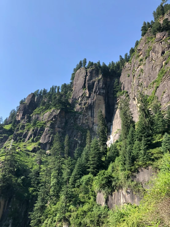 some very tall mountain side with a bunch of trees