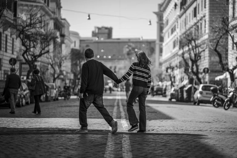 two people holding hands and walking on the street