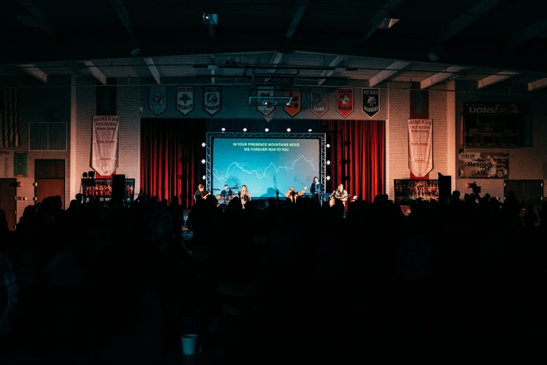 a large screen with people on stage in the dark