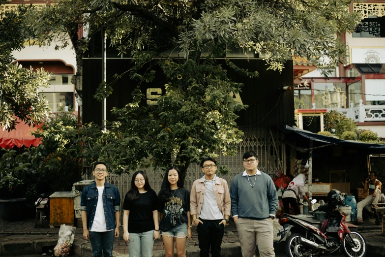 the group is standing under the tree and posing for a po