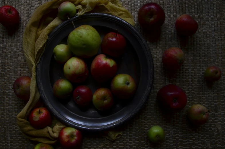 red and green apples sit in a metal bowl