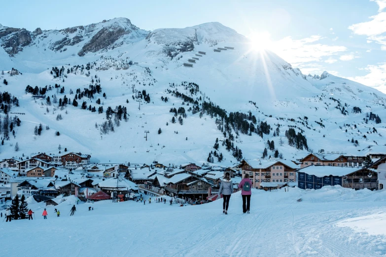 people walking in the snow next to a mountain