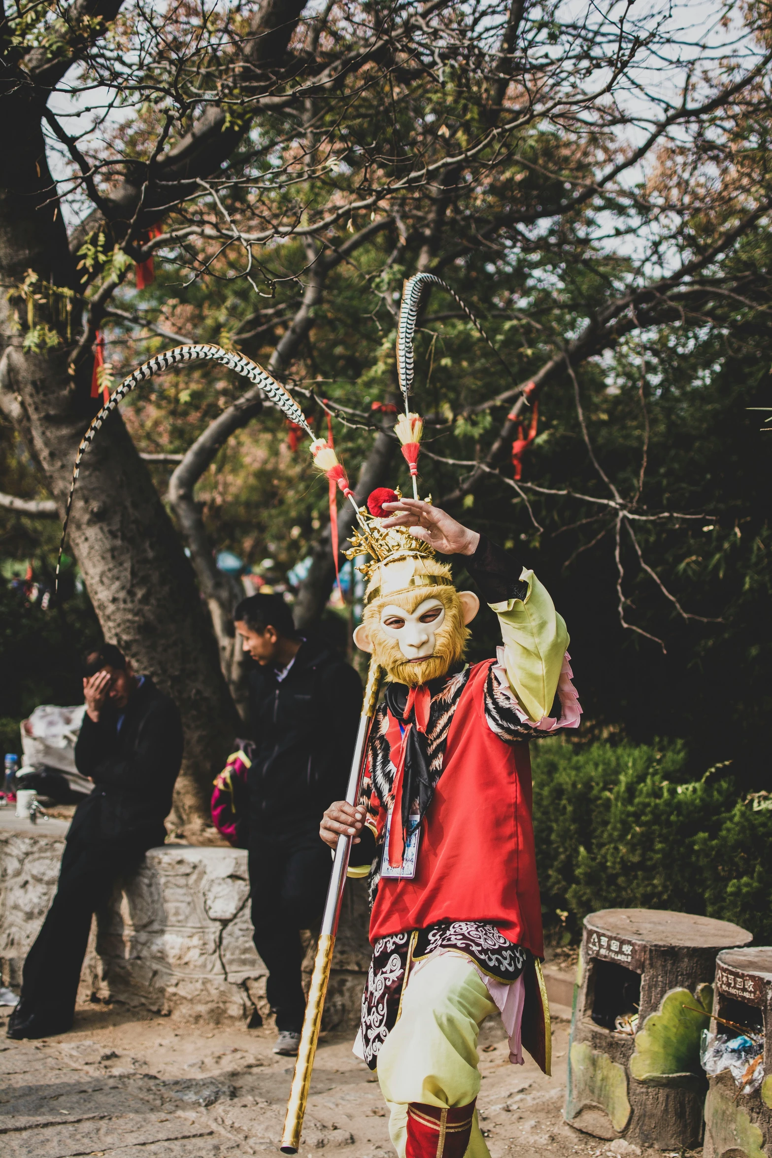 man with a long sword dressed in a mask, some other people around