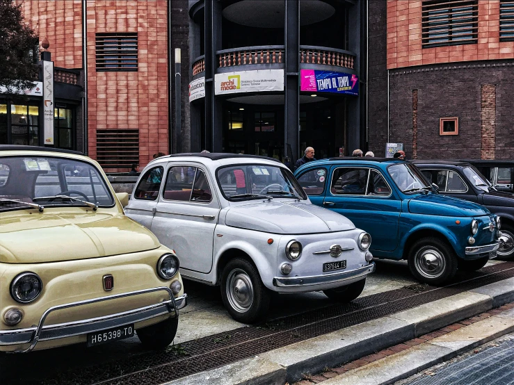 old cars line the curb outside a car show