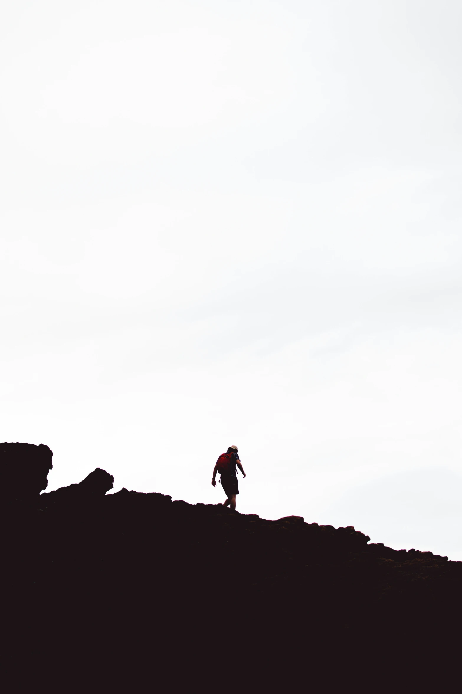 silhouette of a man walking along the edge of a hill