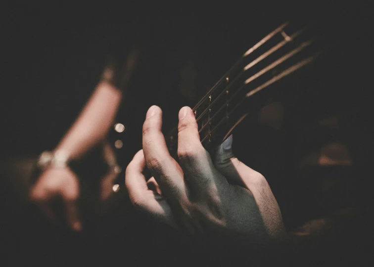 two people holding their guitars in the dark