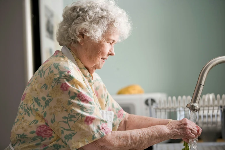 an old woman washing a bottle at a sink