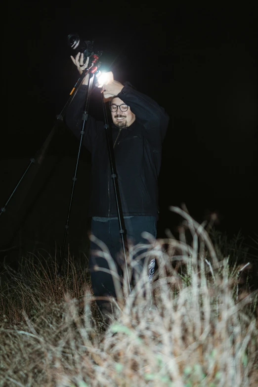 man holding a camera looking through his telescope