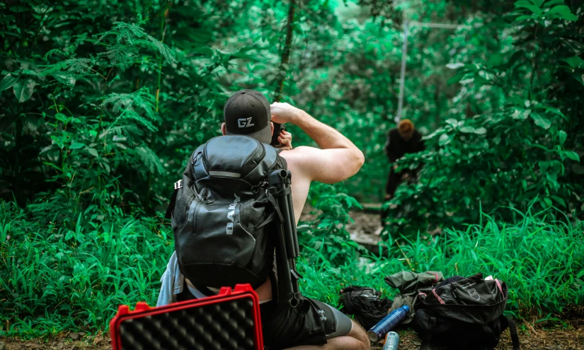 a man sitting in the woods and taking a picture