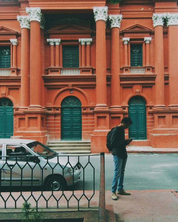 a man is standing in front of an orange building