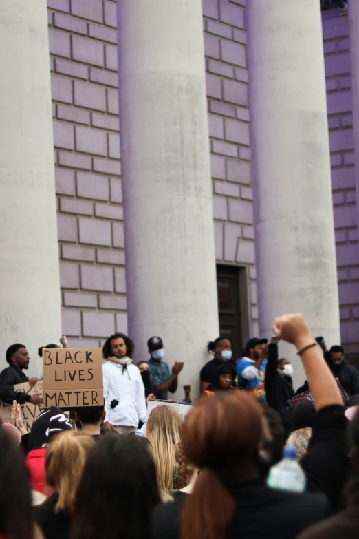 group of people holding signs in protest near pillars