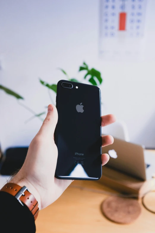 a person holding up an iphone next to a desk