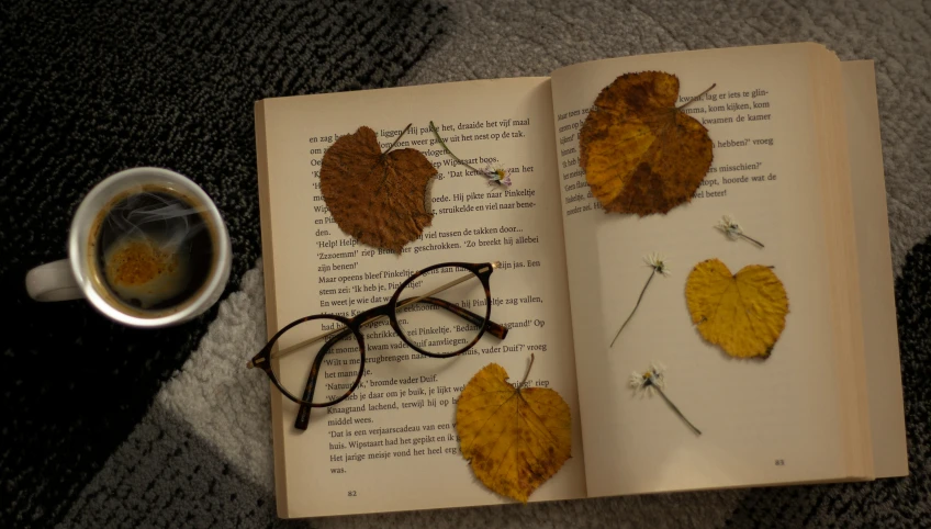 an open book on top of an open book next to a cup of coffee