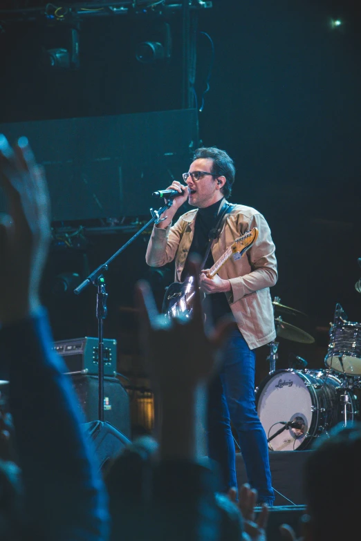 a man playing a guitar on stage while people watch