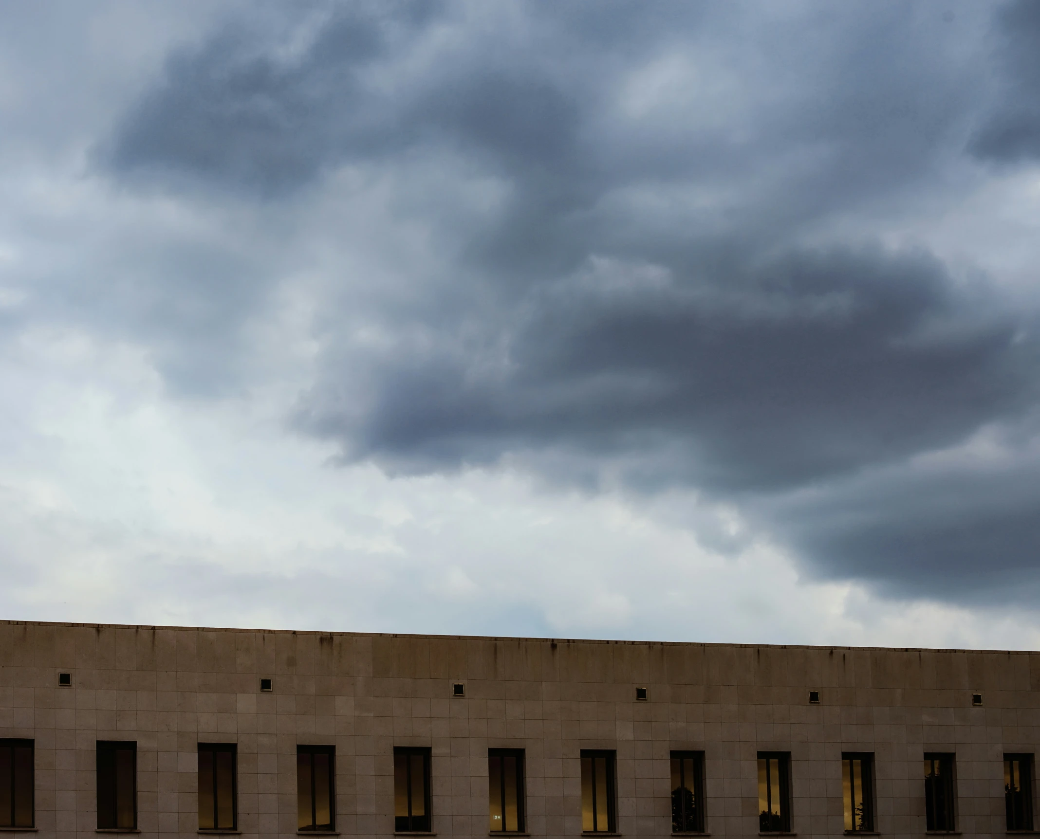 a large building with multiple windows under a cloudy sky