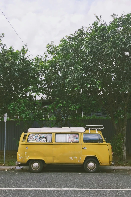 a yellow van is parked in front of a bush