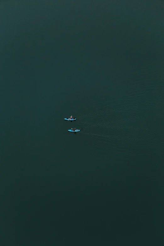 two airplanes flying over the ocean water with blue sails