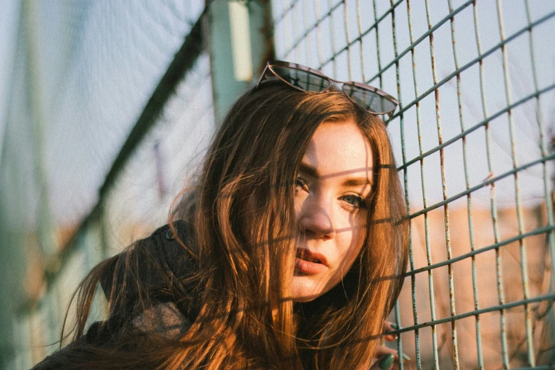 woman leaning against a wire fence in a leather jacket