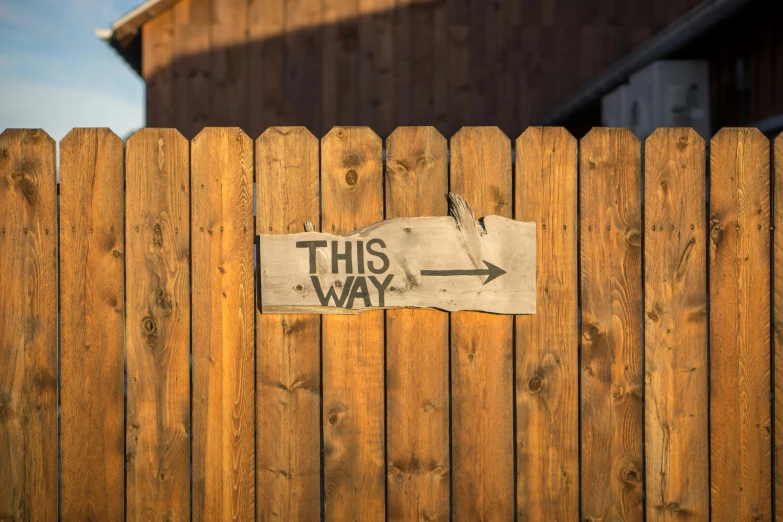 a fence with a sticker attached to it saying, this way