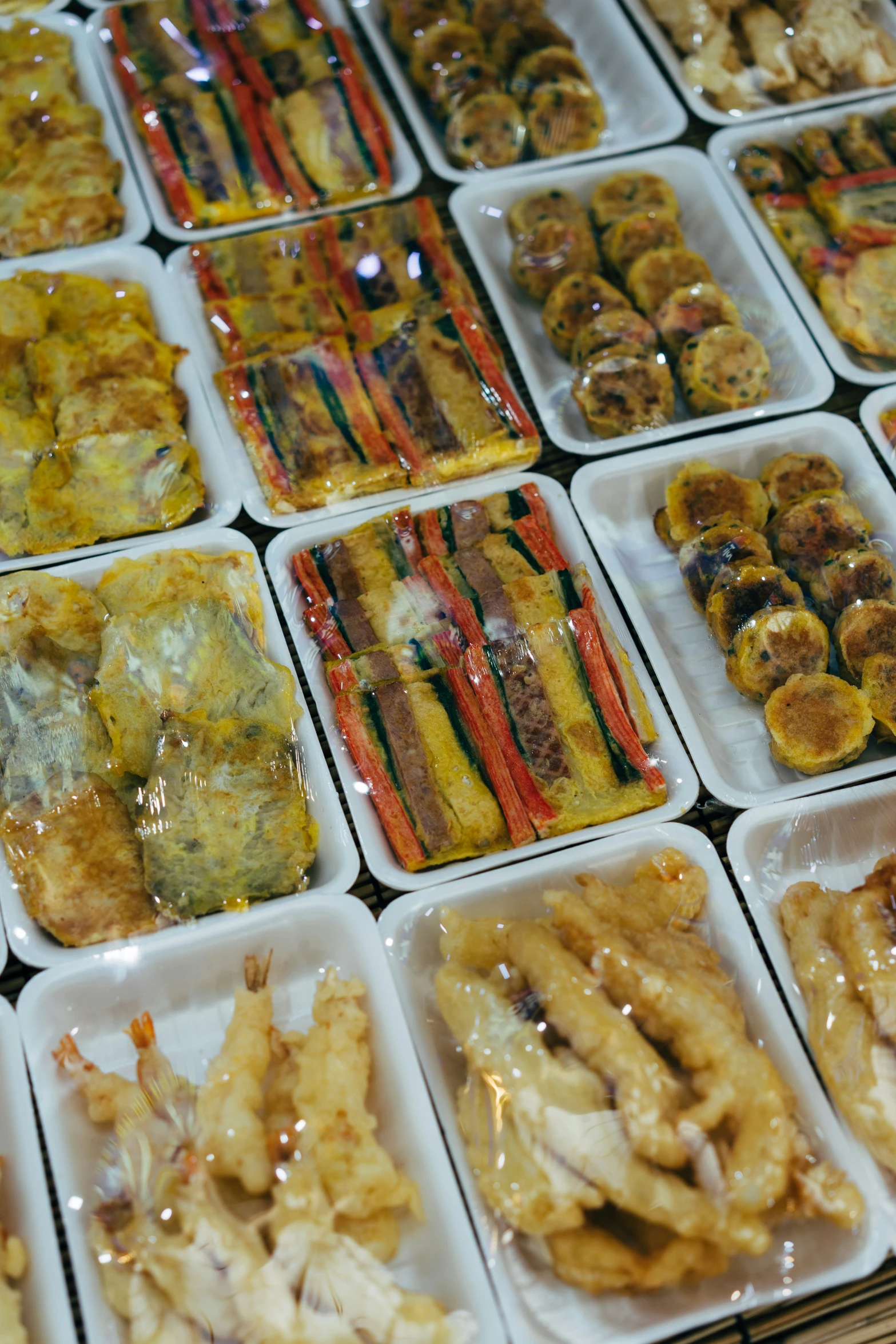 assortment of prepared foods siting in trays on the table