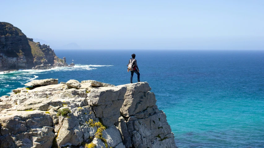 person standing on a rock by the ocean